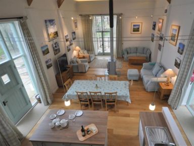 A living room and dining area with sofas a table with chairs and a kitchen island at Leys At Valley View Farm in Uplyme