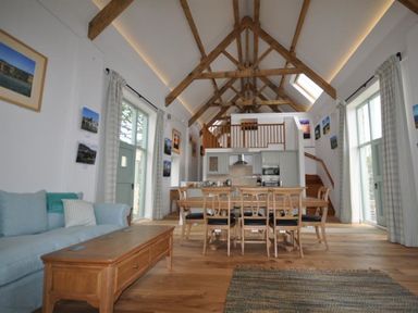 An open-plan living and dining area with wooden beams and a kitchen at Leys At Valley View Farm in Uplyme