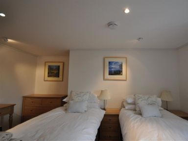 A bedroom with two single beds with pillows and bedside tables with lamps between and beside them at Leys At Valley View Farm in Uplyme