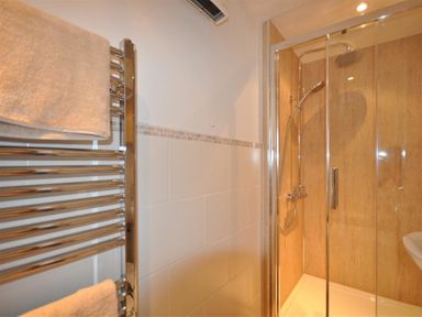 A bathroom with a glass shower enclosure and a towel rack with towels at Leys At Valley View Farm in Uplyme