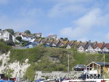 A hillside with houses above a stone wall and a marina with boats at Leys At Valley View Farm in Uplyme