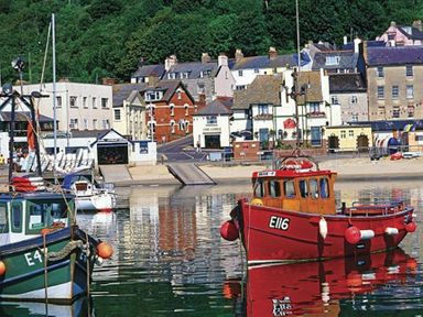 A harbor with small boats in the water and buildings in the background at Leys At Valley View Farm in Uplyme