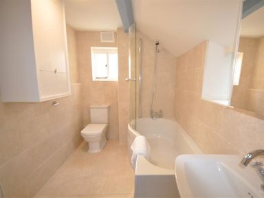 A bathroom with a toilet bathtub shower and sink at Lilac Cottage in Burton Bradstock