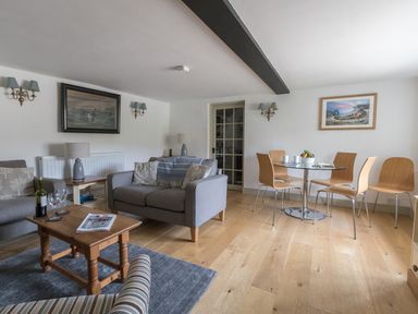 A living room with sofas a coffee table and a dining table with chairs at Little Forge in West Lulworth