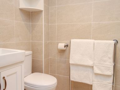 A bathroom with a toilet sink and towel rack with white towels at Little Forge in West Lulworth