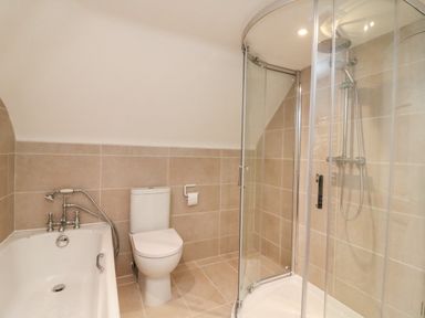 A bathroom with a bathtub toilet and glass shower enclosure at Little Forge in West Lulworth