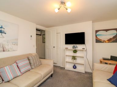 A living room with two beige sofas and a wall-mounted TV at Lobster Cottage Brewers Quay Harbour