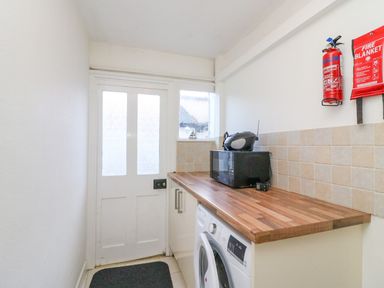 A utility room with a washing machine microwave and fire safety equipment at Lobster Cottage in Brewers Quay Harbour