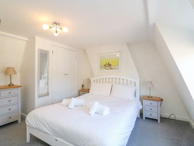 A bedroom with a double bed and white bedding with side tables and lamps at Lobster Cottage Brewers Quay Harbour