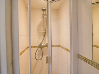 A shower cubicle with a handheld showerhead and tiled walls at Lobster Cottage in Brewers Quay Harbour
