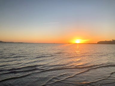 A sunset over the ocean with waves and a distant shoreline at Lobster Cottage in Brewers Quay Harbour
