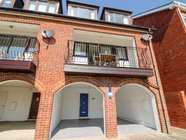 The exterior of a brick building with arches a blue door and a balcony with a table and chairs at Lookout in Cove Castle