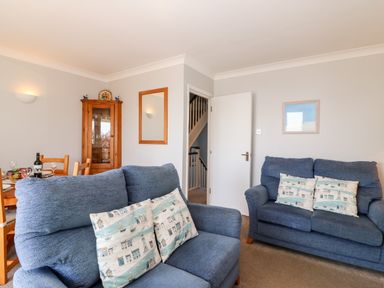 A sitting room with two blue sofas and a wooden dining table with chairs at Lookout in Cove Castle