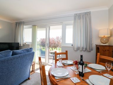 A dining table set with plates and wine glasses next to a blue sofa and sliding glass doors at Lookout in Cove Castle