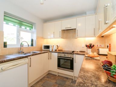 A kitchen with white cabinets a dishwasher an oven a microwave and vegetables in a basket at Lookout in Cove Castle