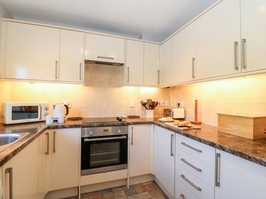 A kitchen with white cabinets a microwave kettle oven utensils toaster and bread on the counter at Lookout in Cove Castle