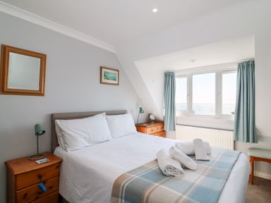 A bedroom with a bed with white linens and rolled towels near a window with blue curtains at Lookout in Cove Castle