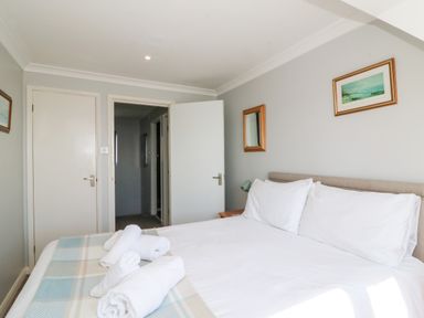 A bedroom with a bed with white linens and towels on it and doors and pictures on the walls at Lookout in Cove Castle