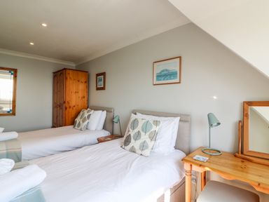 A bedroom with two single beds a wooden wardrobe a desk with a lamp and a mirror at Lookout in Cove Castle