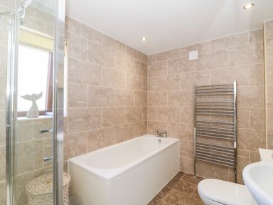 A bathroom with a bathtub a heated towel rail a toilet and a window at Lookout in Cove Castle