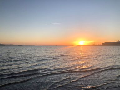 A sunset over a calm sea with gentle waves and distant ships at Lookout in Cove Castle