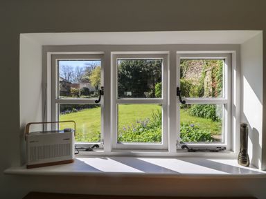 A window with a radio on the left and a flashlight on the right looking out to a garden at Lychgate Cottage in Osmington