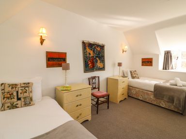 A bedroom with two single beds bedside tables lamps and a chair at Lychgate Cottage in Osmington
