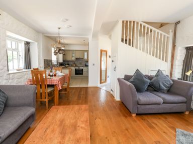 A living room and kitchen area with wooden floor and dining table at Magnolia Cottage Osmington