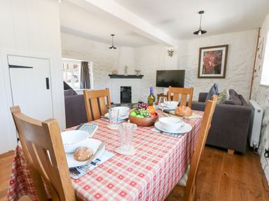 A dining table with plates bowls glasses and food in a living room with a TV sofa and fireplace at Magnolia Cottage Osmington
