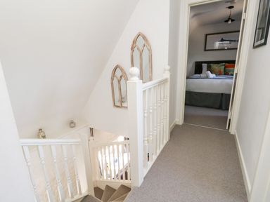 A hallway with a staircase and a bedroom visible at the end of the hall at Magnolia Cottage Osmington