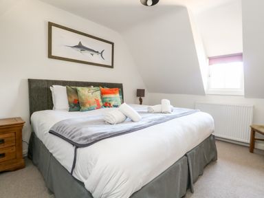 A bedroom with a bed with pillows and rolled towels a nightstand and a window at Magnolia Cottage Osmington in Osmington
