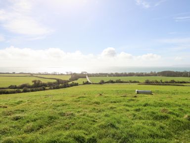 A landscape with green fields and a distant view of the sea at Magnolia Cottage Osmington