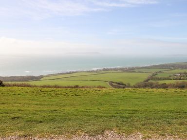 A coastal landscape with green fields and the sea in the distance at Magnolia Cottage Osmington