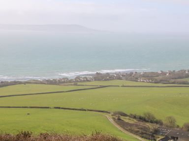 A coastal landscape with green fields and sheep near houses by the sea at Magnolia Cottage Osmington
