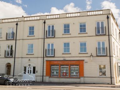 A three-story building with white walls and multiple windows and an orange framed shop window at Marina Vista in Weymouth