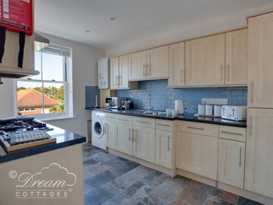 A kitchen with wooden cabinets black countertops blue tile backsplash and appliances at Marina Vista in Weymouth