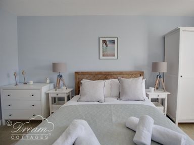A bedroom with a double bed two bedside tables with lamps a chest of drawers and a wardrobe at Marina Vista in Weymouth