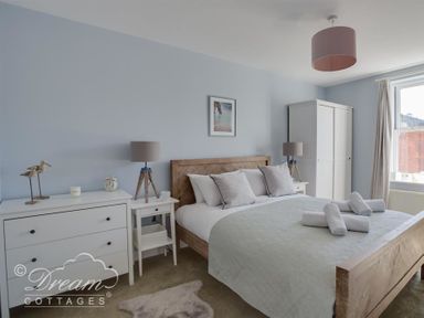 A bedroom with a wooden bed white bedside tables white wardrobe and a chest of drawers at Marina Vista in Weymouth