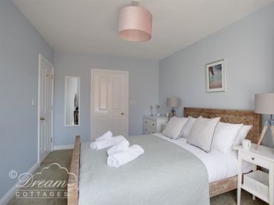 A bedroom with a double bed with rolled towels on it bedside tables with lamps and a mirror on the wall at Marina Vista in Weymouth