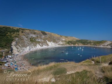 A bay with boats on water and a beach with people near cliffs at Marina Vista in Weymouth