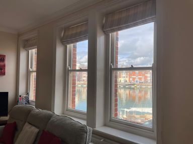 A living room with windows overlooking a harbor at Mutiny House in Brewers Quay Harbour