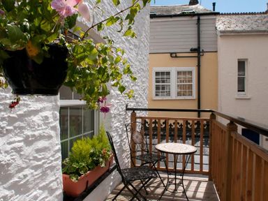 A small balcony with two chairs a round table and plants on the railing at Courtyard House Dartmouth