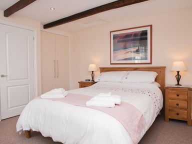 A bedroom with a bed and wooden bedside tables with lamps at Courtyard House in Dartmouth