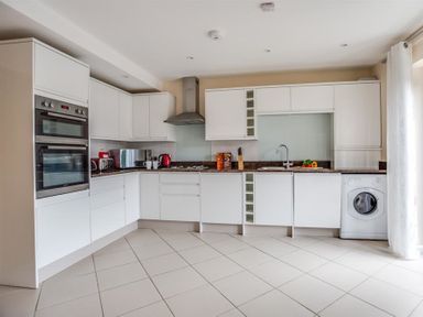 A kitchen with white cabinets appliances and a tiled floor at New Boathouse in Weymouth