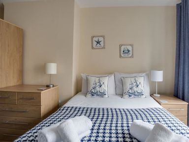 A bedroom with a double bed two bedside tables with lamps and wooden chest of drawers at New Boathouse in Weymouth