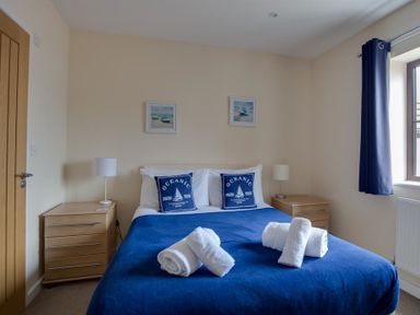 A bedroom with a bed covered in a blue bedspread and two pillows with oceanic designs at New Boathouse in Weymouth