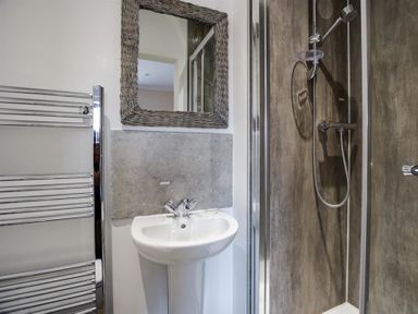A bathroom with a pedestal sink mirror towel rack and a shower at New Boathouse in Weymouth