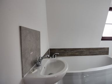 A bathroom with a white sink and bathtub with a window at New Boathouse in Weymouth