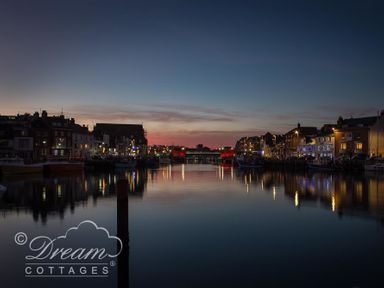 A waterfront with buildings and boats along the sides at New Boathouse in Weymouth
