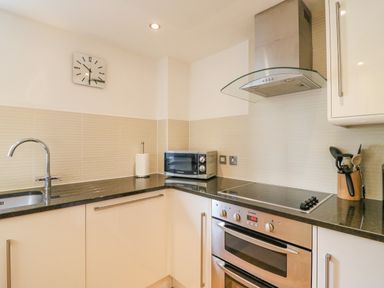 A kitchen area with a sink a microwave oven a stovetop and utensils at Newton's Cove View in Weymouth